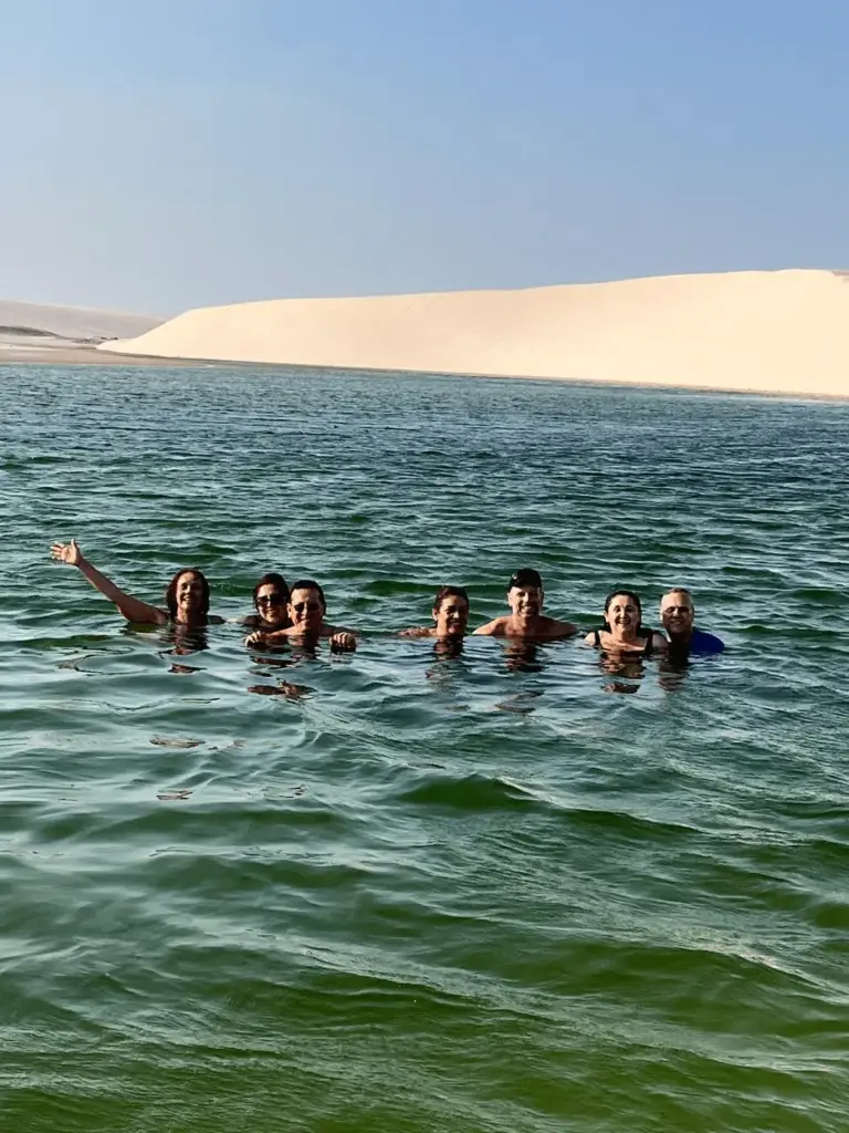 O espetáculo do pôr do sol transforma as lagoas dos Lençóis Maranhenses em um cenário inesquecível. Grupo de turistas KG VIAGENS aproveitando as águas cristalinas.