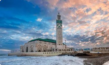 Vista da Mesquita Hassan II em Casablanca, Marrocos, com o Oceano Atlântico ao fundo durante o entardecer.